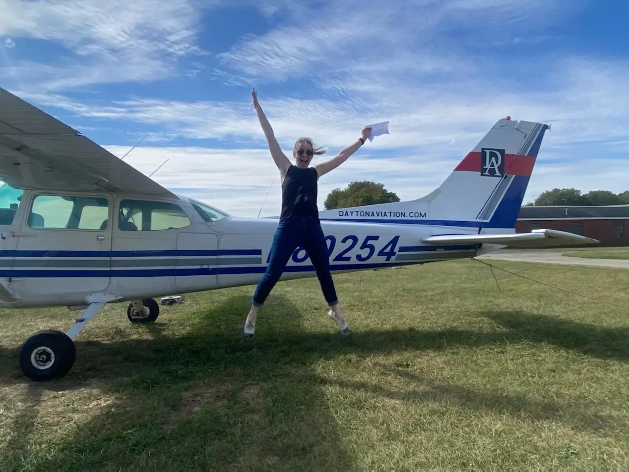 Pilot celebrating a flight training milestone beside an airplane